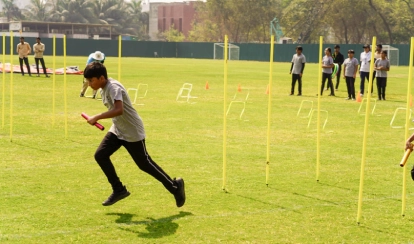 Student runs with a baton during a relay race on the school field.