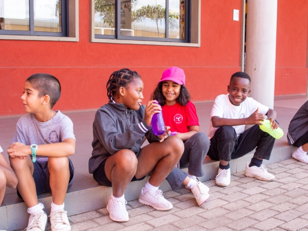 A parent stands in front of a “Welcome to our Unit Display” sign at AKA Dhaka.
