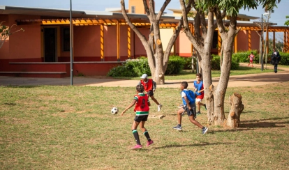AKA Maputo students playing football in an open field.