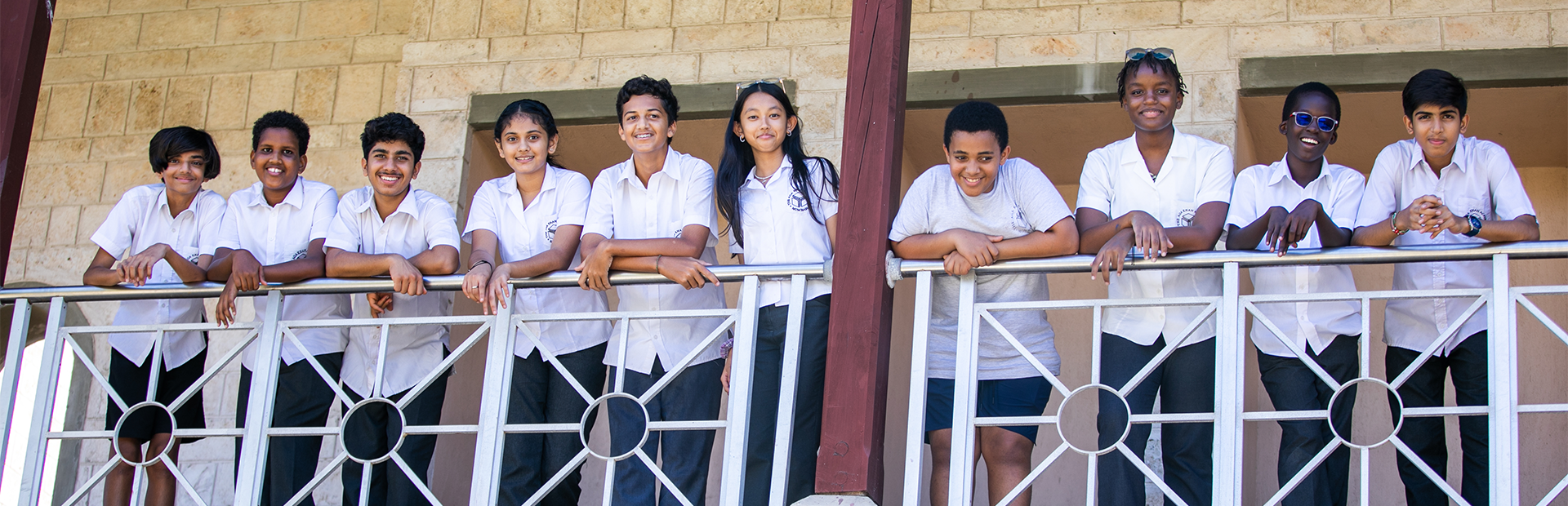 Students standing on a balcony and smiling.