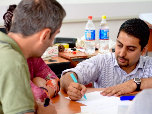 Malik Mahedmood sits at his desk with a laptop, smiling while working in his office