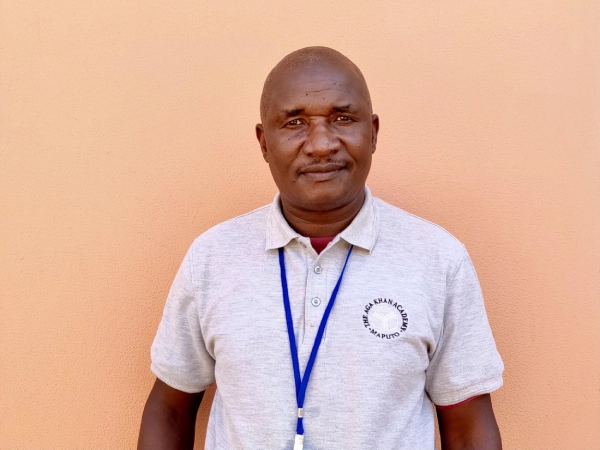Malik Mahedmood sits at his desk with a laptop, smiling while working in his office