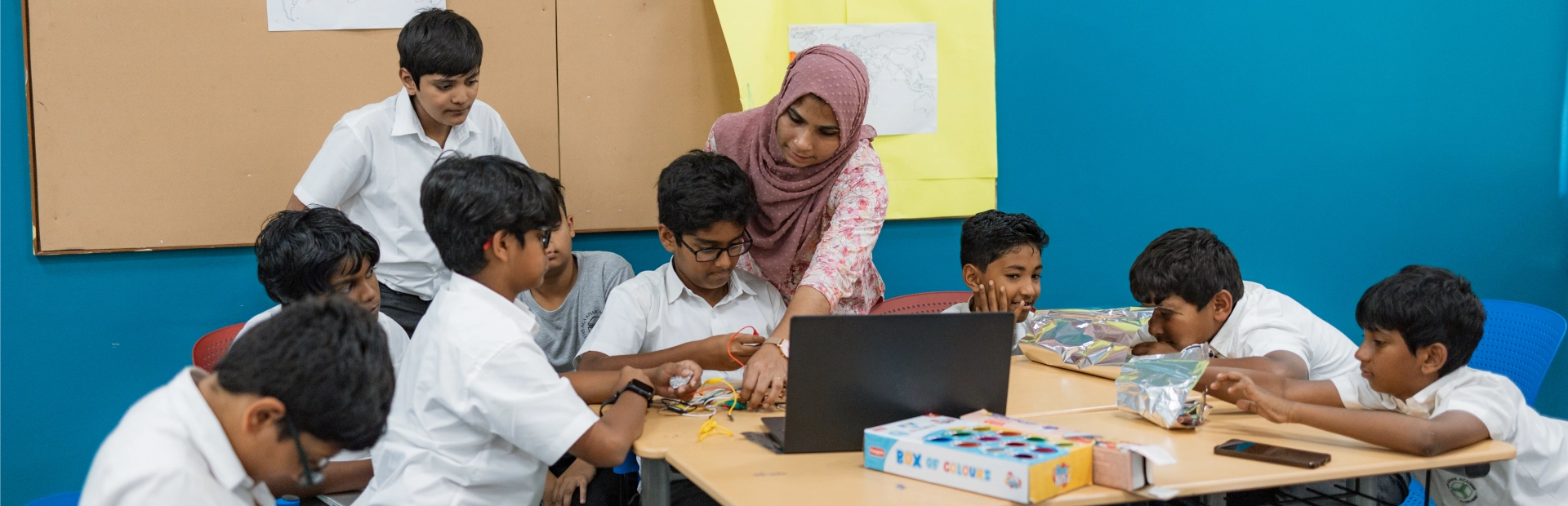 Students work together on a science experiment with beakers and droppers in a lab.