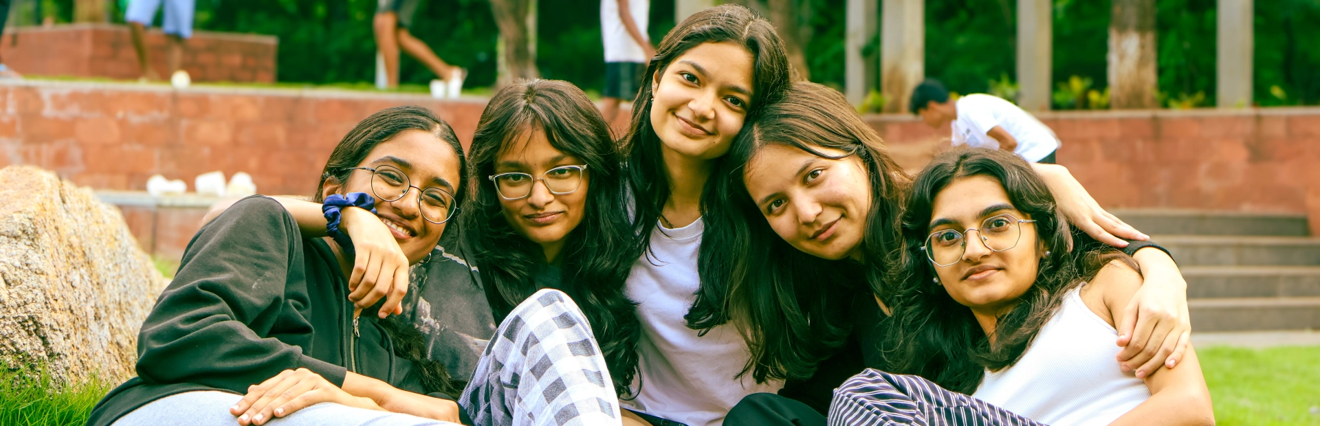 Students sitting together on the grass, looking at the camera.