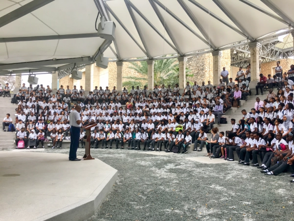 Students and teachers gathered in an amphitheatre with a teacher standing at a podium.