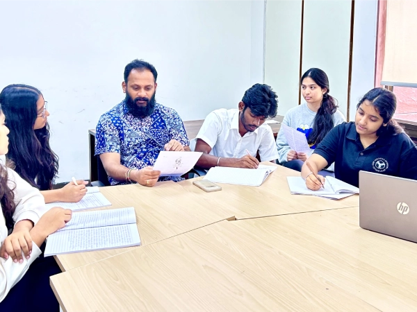 A student presents their theory of knowledge exhibition display to a visitor, discussing ideas about knowledge and understanding.