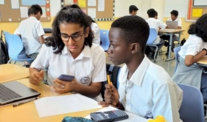 A group of students at AKA Dhaka sit around a table in the art studio, painting vibrant artworks on canvas with brushes and pastels.