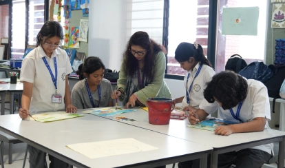 Students and a teacher work together on painting projects in an art classroom.