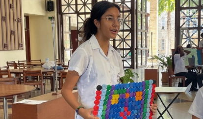 Student holding a bathmat made from recycled plastic bottles.