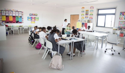A group of students at AKA Dhaka sit around a table in the art studio, painting vibrant artworks on canvas with brushes and pastels.