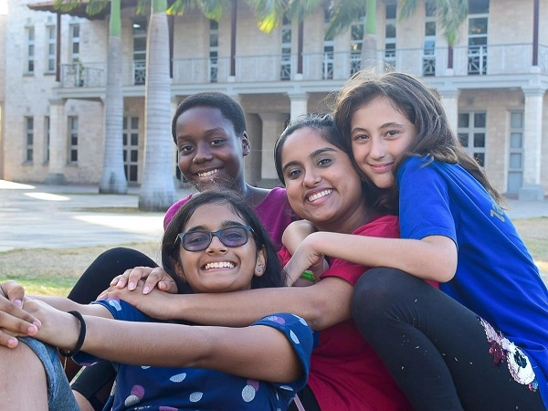 Dorm parent sitting on the grass with a group of happy girls