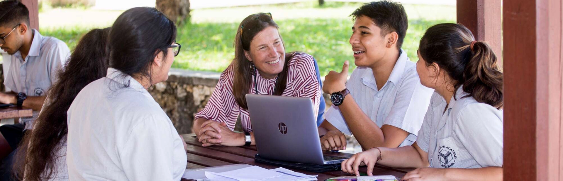 Students and a staff member having a discussion outdoors.