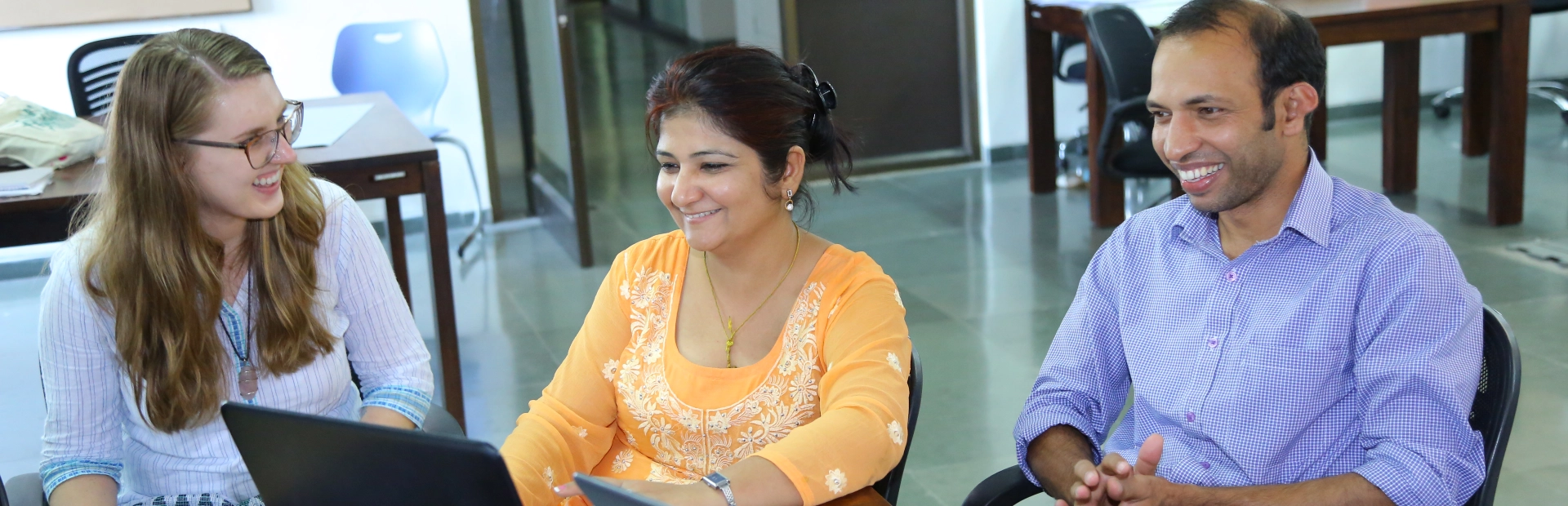 Teachers sitting together, smiling at each other.