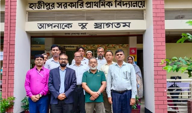A group of educators and professionals stand in front of a government primary school during a PDC field visit for the KIX project observation.