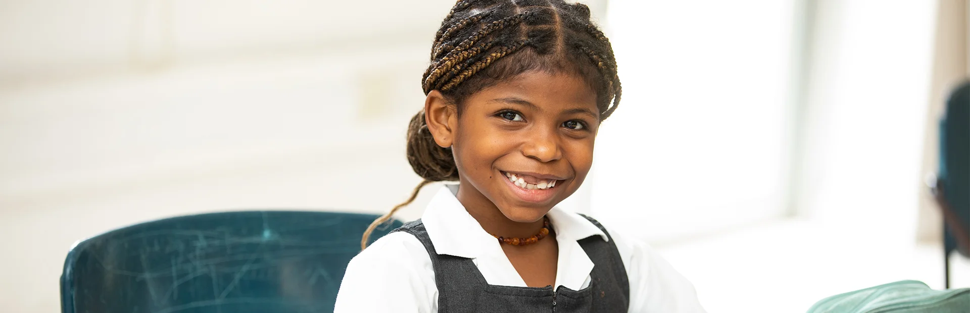 Junior school student working at her desk and smiling.