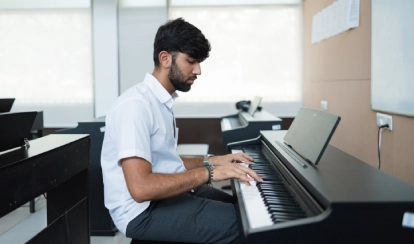  A student in uniform gestures with his hands to form a frame while performing in a drama class.