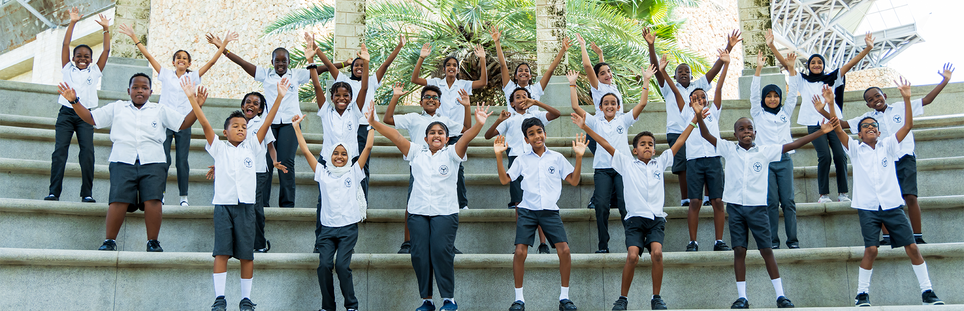 A group of parents and students are smiling and looking at the camera while standing in front of a signage for an event at the Academy