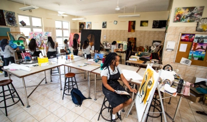 Student playing cricket on astroturf.