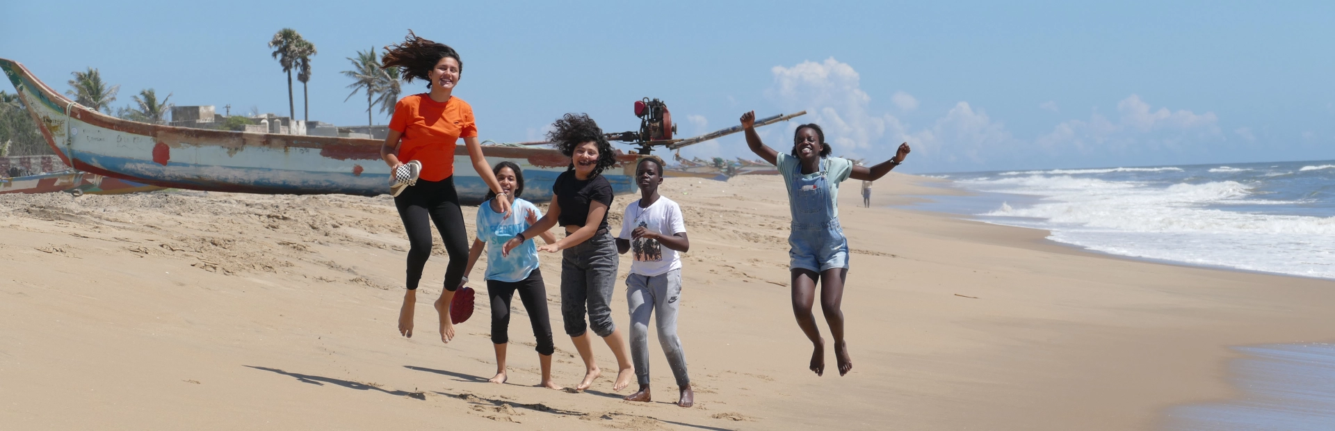 Students jumping up in the air on a beach.