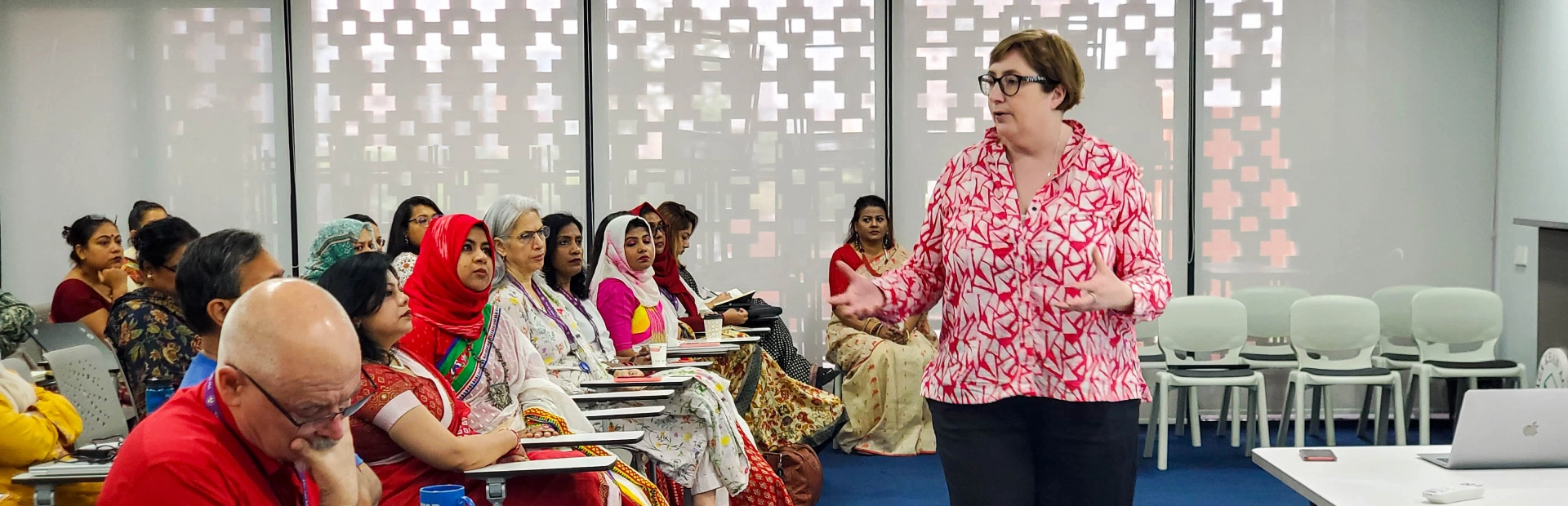 An instructor speaks to a group of teachers seated in a classroom during a professional development session at the Aga Khan Academy Dhaka.