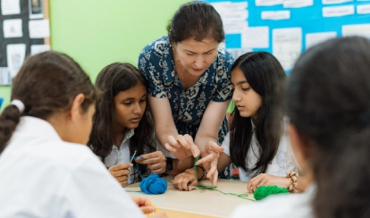 A teacher guiding students to knit.