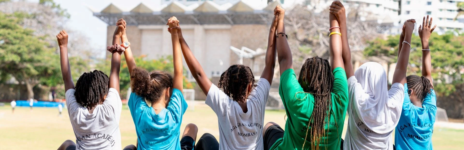  Students sitting together with their hands raised.