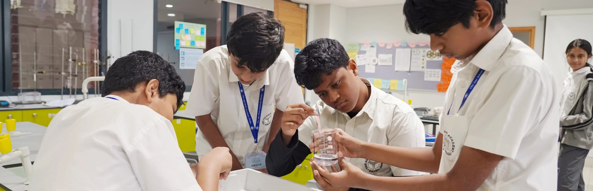 Students work together on a science experiment with beakers and droppers in a lab.