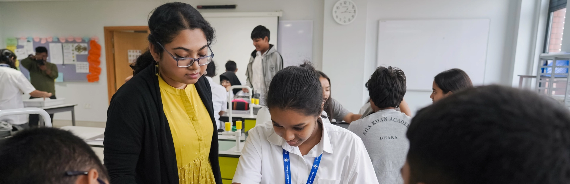  A teacher guides students during a science experiment in a classroom at the Aga Khan Academy Dhaka, fostering collaboration and hands-on learning.